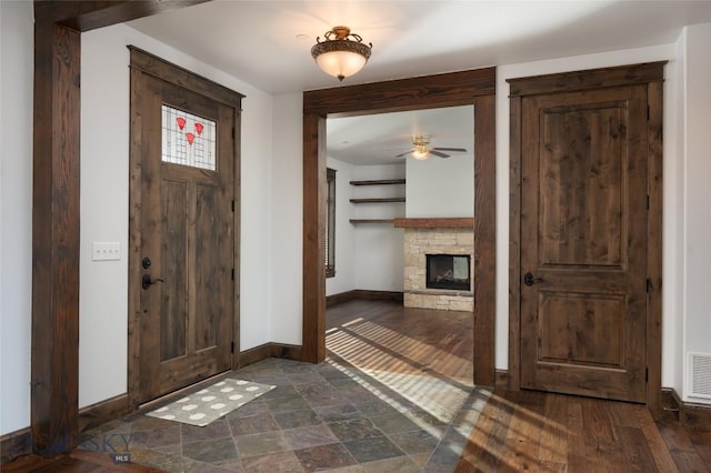 foyer entrance with dark hardwood / wood-style floors, ceiling fan, and a fireplace