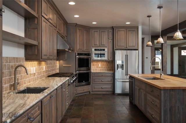 kitchen featuring stainless steel appliances, pendant lighting, sink, and wooden counters