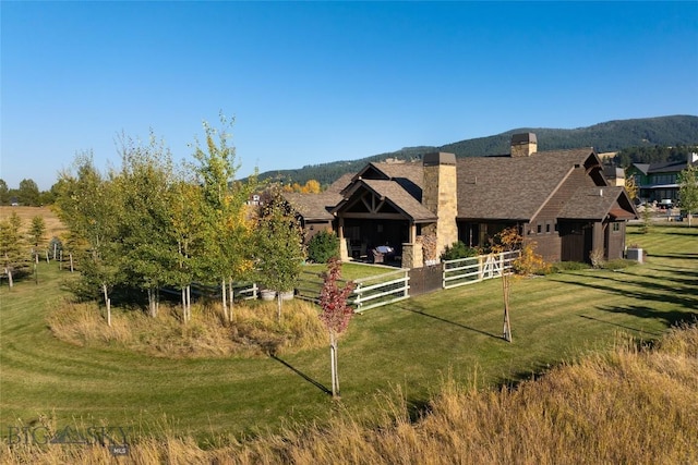 view of front of home with a mountain view, a front lawn, and central AC unit