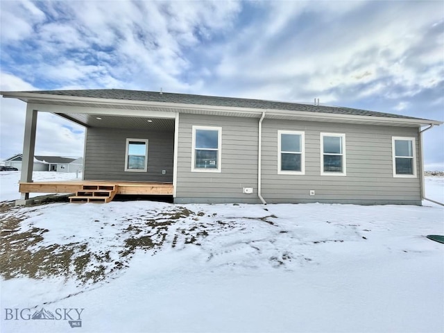 snow covered rear of property featuring a deck