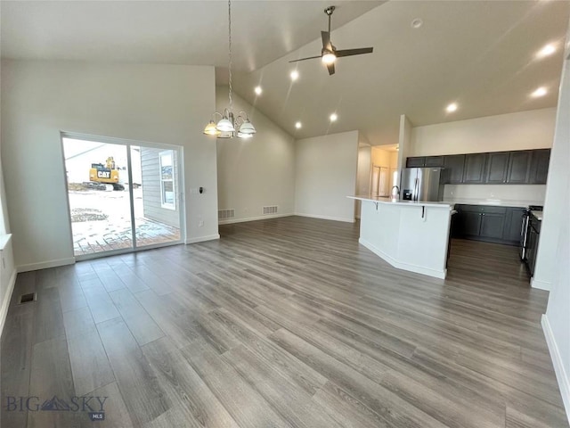 unfurnished living room featuring hardwood / wood-style floors, ceiling fan with notable chandelier, and high vaulted ceiling