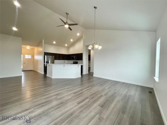 unfurnished living room with high vaulted ceiling, light hardwood / wood-style floors, and ceiling fan with notable chandelier