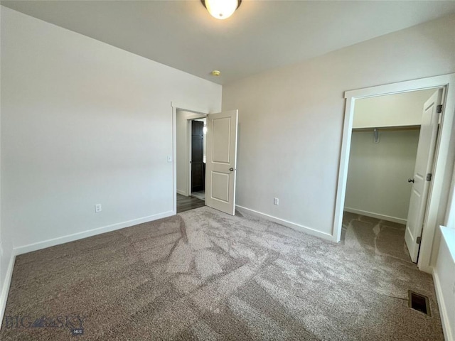 unfurnished bedroom featuring carpet flooring, a walk in closet, and a closet