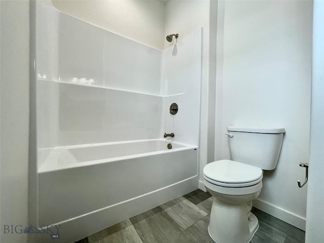 bathroom with hardwood / wood-style flooring, toilet, and bathing tub / shower combination