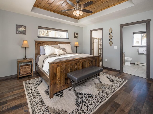 bedroom featuring multiple windows, dark hardwood / wood-style flooring, a raised ceiling, and ensuite bath