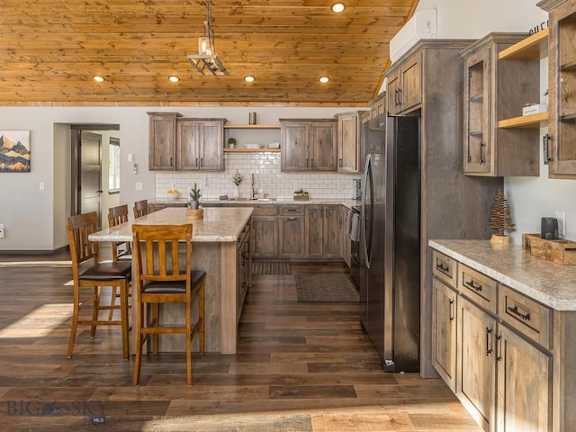 1880 Little Coyote, Big Sky, MT 59716 - kitchen featuring open shelves, stainless steel refrigerator with ice dispenser, wood ceiling, a center island, and a breakfast bar