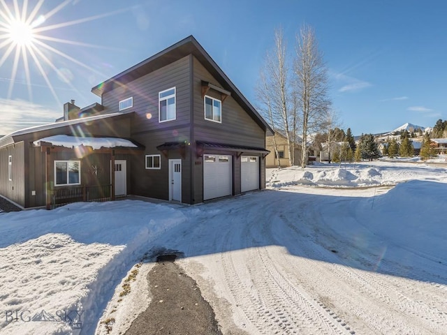 snow covered property with a garage