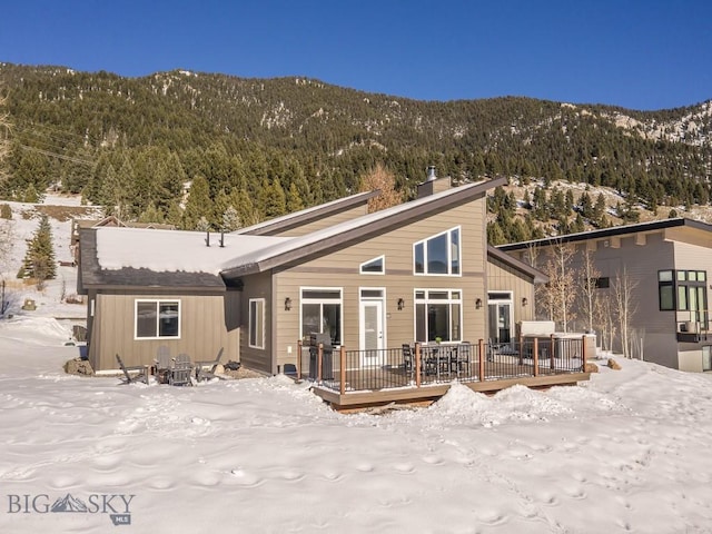 snow covered rear of property featuring a deck with mountain view