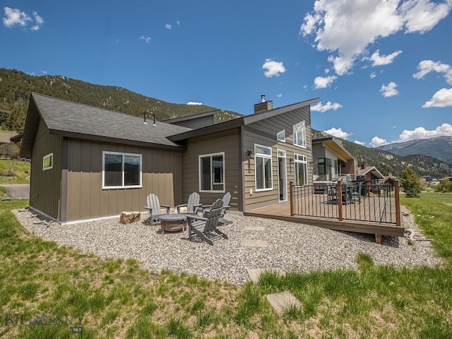 1880 Little Coyote, Big Sky, MT 59716 - back of house with an outdoor fire pit, a deck with mountain view, and a chimney