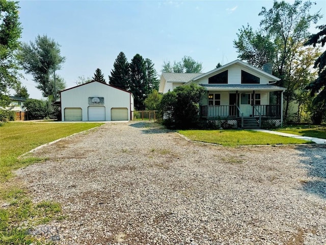 view of front of home featuring covered porch, a garage, an outbuilding, and a front yard