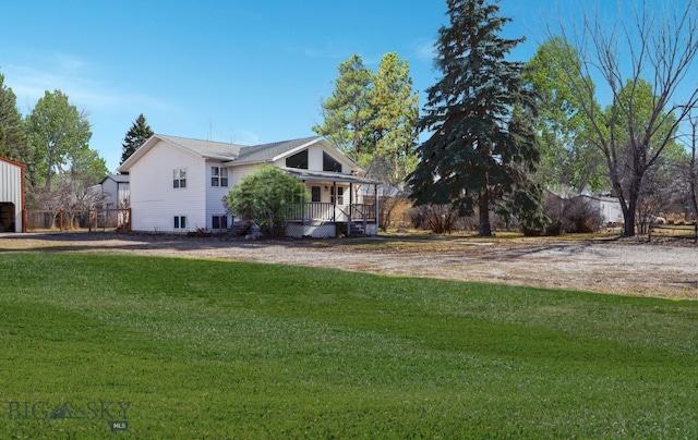 view of side of property with covered porch and a lawn