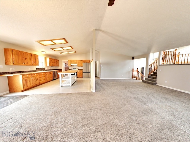 unfurnished living room featuring sink, light colored carpet, lofted ceiling, and a textured ceiling