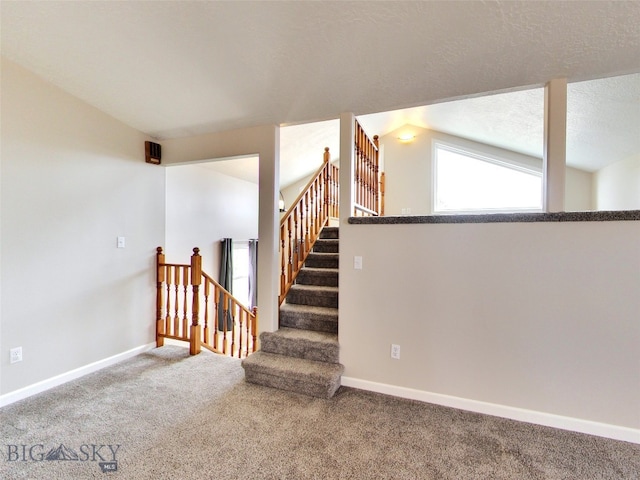 staircase with a textured ceiling, carpet, and lofted ceiling