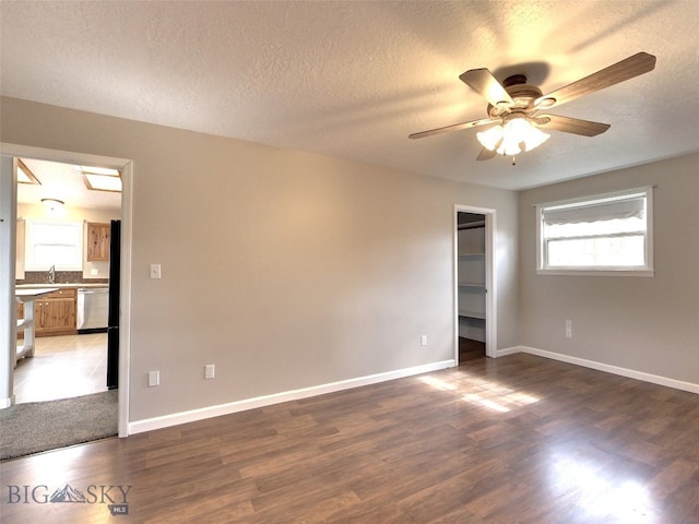 empty room featuring a textured ceiling, ceiling fan, sink, and dark hardwood / wood-style floors