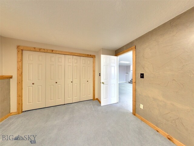 unfurnished bedroom with carpet flooring, a textured ceiling, and a closet