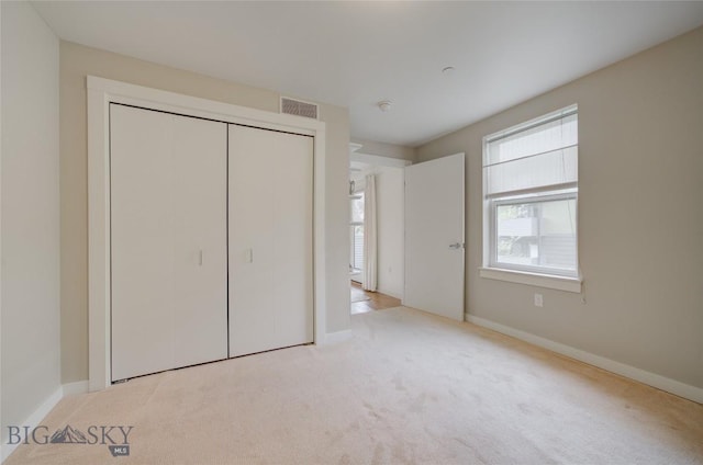 unfurnished bedroom with light colored carpet and a closet