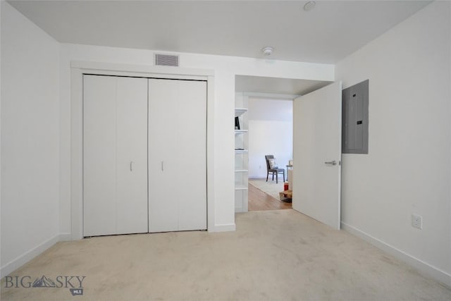 unfurnished bedroom with electric panel, light carpet, and a closet