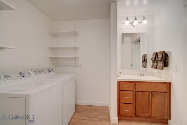 laundry area with washing machine and dryer, light hardwood / wood-style flooring, and sink