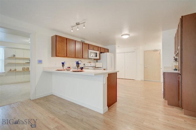 kitchen with kitchen peninsula, white appliances, and light hardwood / wood-style flooring