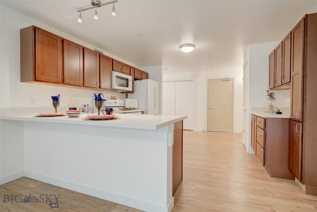 kitchen with kitchen peninsula, light hardwood / wood-style flooring, and white appliances