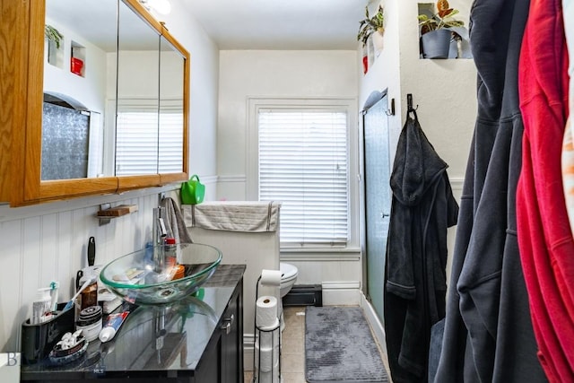 bathroom with tile patterned floors, vanity, toilet, and a shower with door