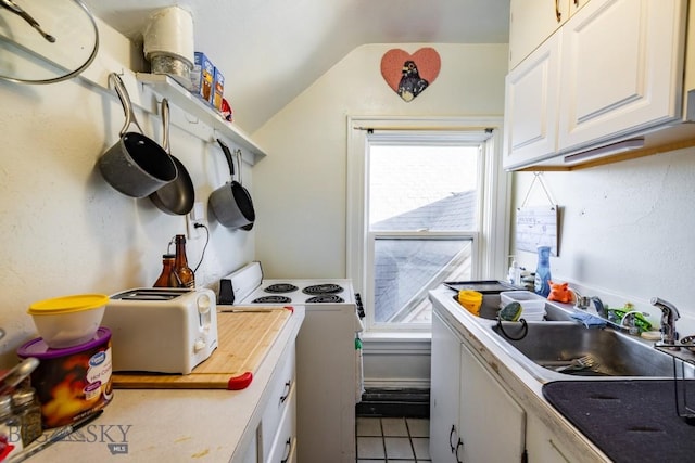 kitchen with sink, white cabinets, washer / dryer, lofted ceiling, and light tile patterned flooring