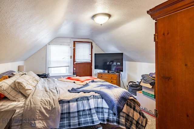 carpeted bedroom featuring a textured ceiling and lofted ceiling