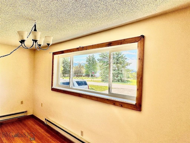 empty room featuring a textured ceiling, dark hardwood / wood-style floors, baseboard heating, and a notable chandelier