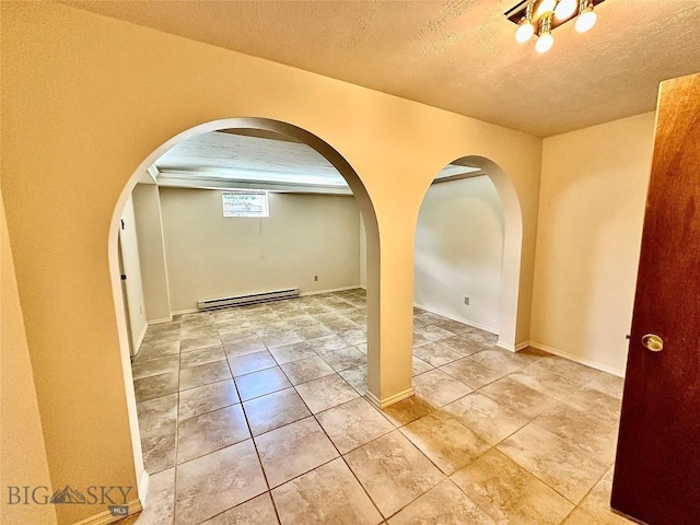 empty room with tile patterned flooring, a textured ceiling, and a baseboard radiator