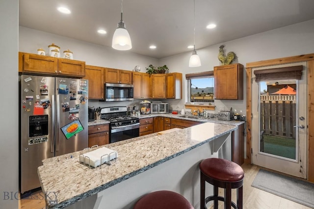 kitchen featuring a kitchen bar, appliances with stainless steel finishes, light stone counters, sink, and pendant lighting