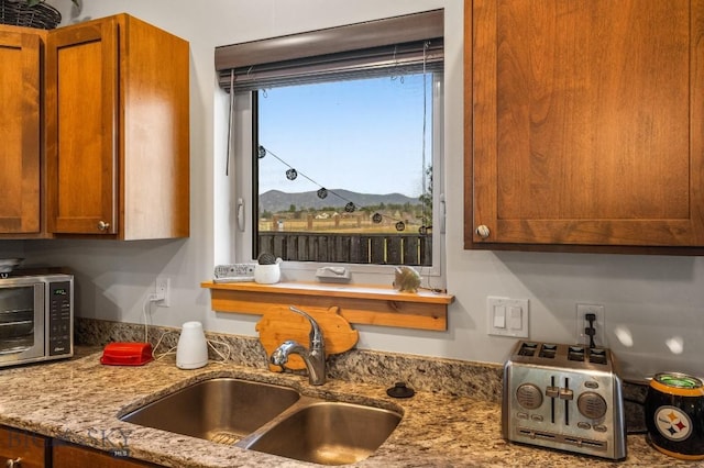 kitchen with a mountain view, sink, and light stone countertops