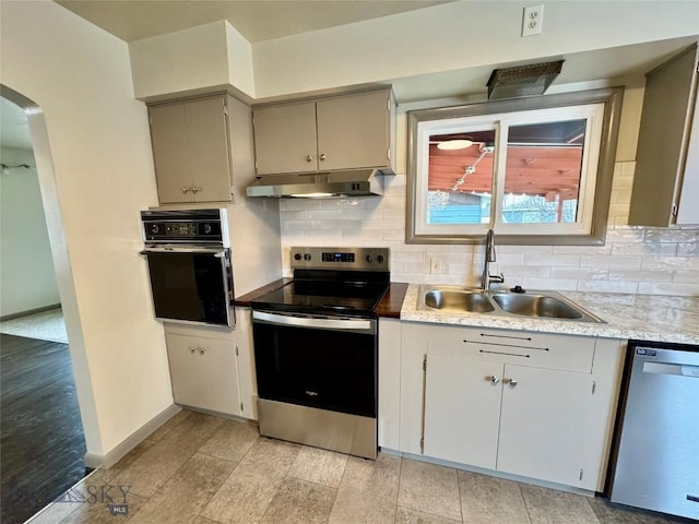 kitchen with decorative backsplash, appliances with stainless steel finishes, light hardwood / wood-style flooring, and sink