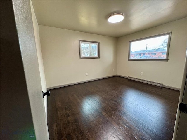 unfurnished room featuring a healthy amount of sunlight, dark hardwood / wood-style flooring, and a baseboard heating unit