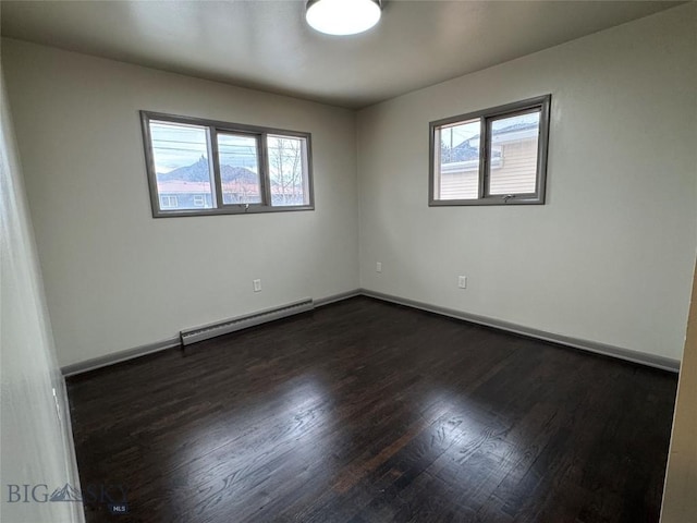 spare room with dark wood-type flooring, a wealth of natural light, and a baseboard heating unit