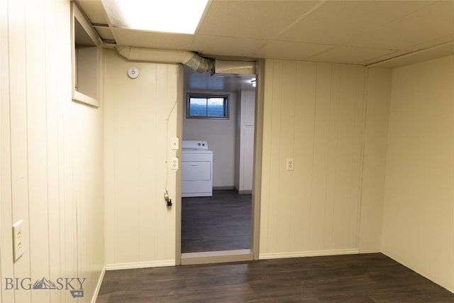 basement featuring a drop ceiling, washer / clothes dryer, dark hardwood / wood-style floors, and wood walls