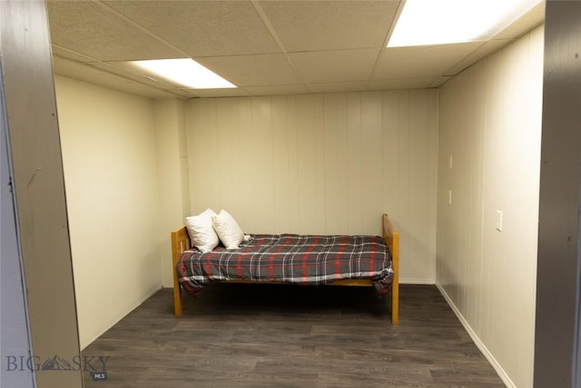 bedroom with a paneled ceiling and dark hardwood / wood-style flooring