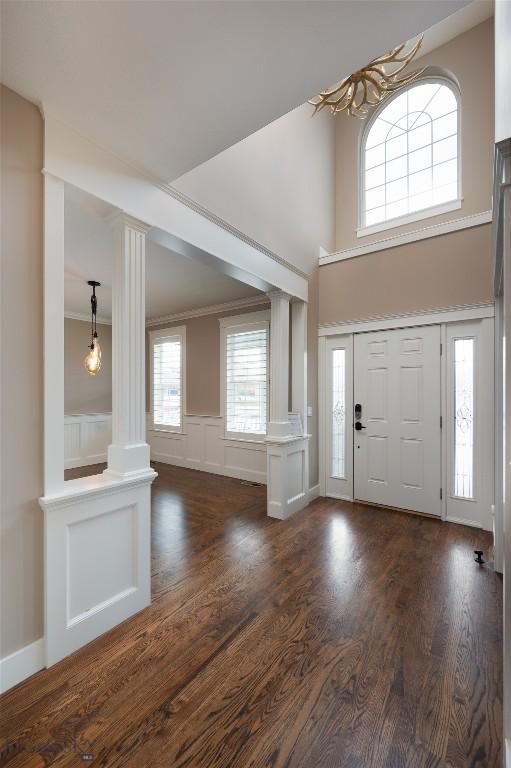 foyer with ornate columns, dark wood-type flooring, and a wealth of natural light