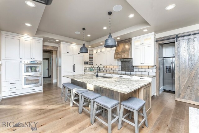 4807 Jordan Spur Rd, Bozeman, MT 59715 - kitchen with a raised ceiling, appliances with stainless steel finishes, custom exhaust hood, white cabinets, and recessed lighting