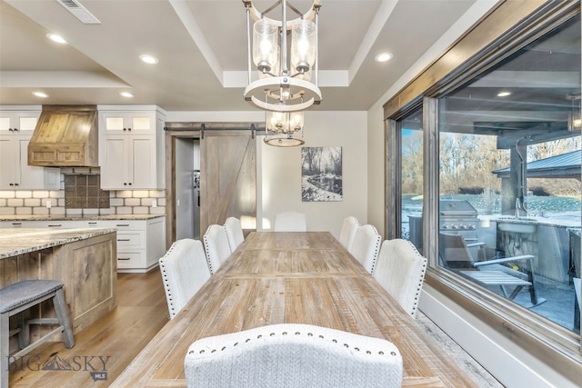 4807 Jordan Spur Rd, Bozeman, MT 59715 - dining room with a barn door, a raised ceiling, a chandelier, light wood-type flooring, and recessed lighting