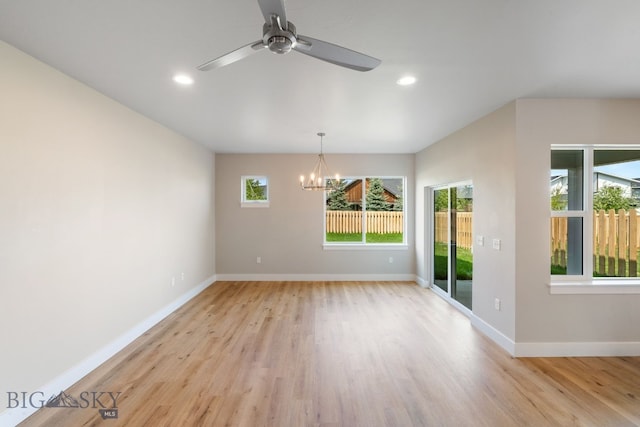 spare room featuring light hardwood / wood-style flooring, a healthy amount of sunlight, and ceiling fan with notable chandelier