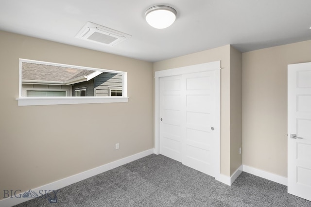 unfurnished bedroom with multiple windows, a closet, and dark colored carpet