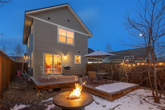 snow covered back of property featuring a wooden deck and a fire pit