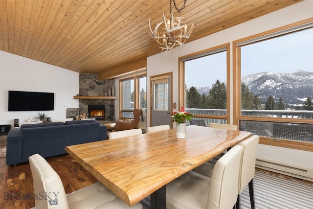 dining area featuring a mountain view, wooden ceiling, a fireplace, and a baseboard heating unit