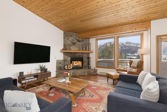 living room with vaulted ceiling, wooden ceiling, a mountain view, hardwood / wood-style floors, and a stone fireplace