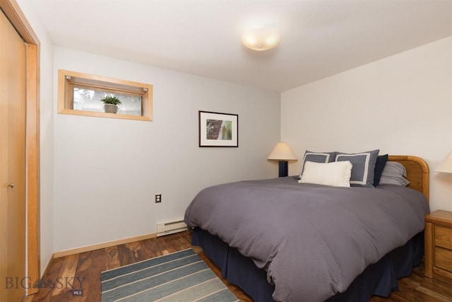 bedroom with dark hardwood / wood-style floors, a closet, and a baseboard heating unit