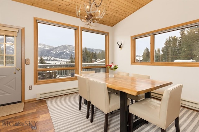 dining area with vaulted ceiling, baseboard heating, wooden ceiling, a notable chandelier, and a mountain view