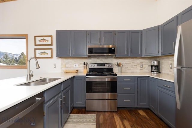 kitchen featuring dark hardwood / wood-style flooring, tasteful backsplash, gray cabinetry, stainless steel appliances, and sink