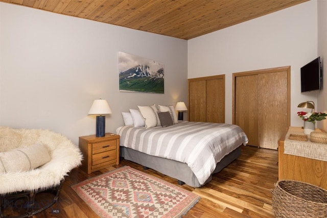 bedroom with multiple closets, wooden ceiling, and dark wood-type flooring