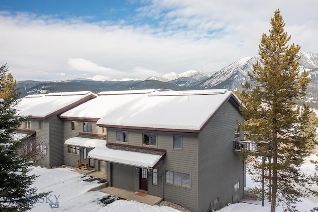 snow covered rear of property with a mountain view