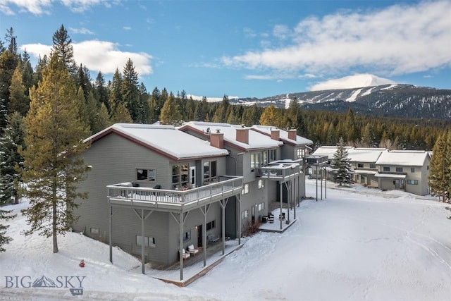 snow covered property with a deck with mountain view